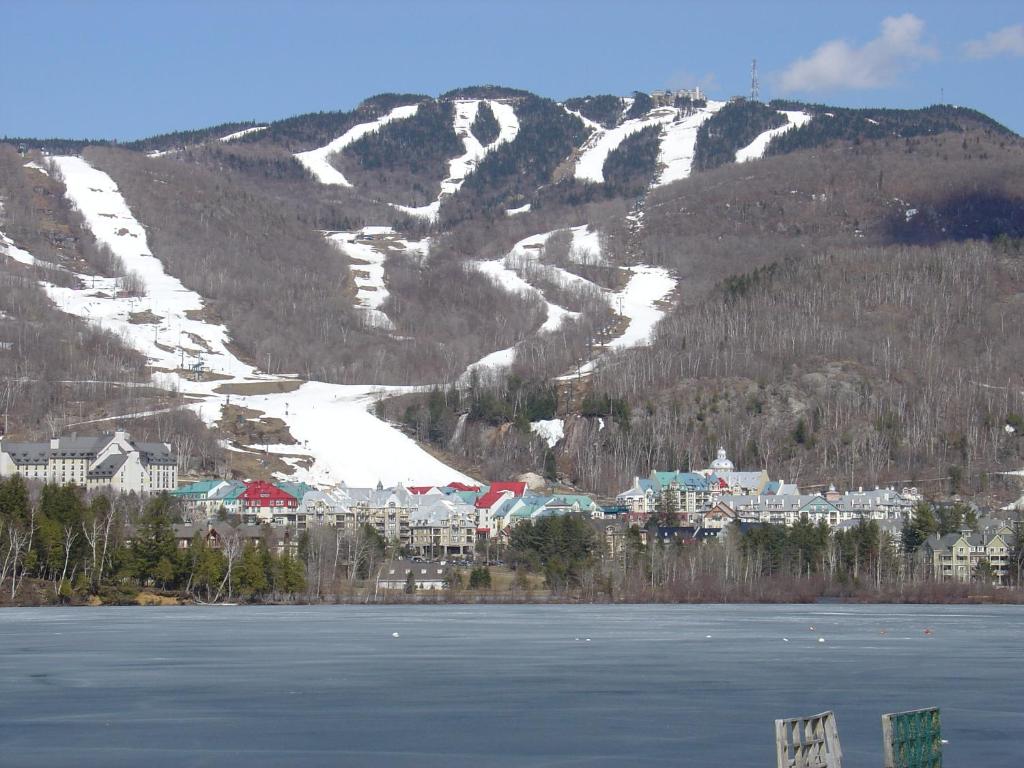 a snowy mountain with a town and a body of water at Mont-Tremblant in Mont-Tremblant