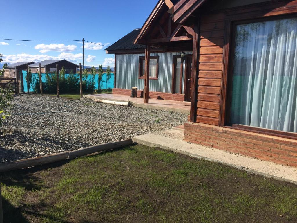 une cabane en rondins avec une cour gazonnée à côté d'une maison dans l'établissement Casa Patagónica Los Frutales, à El Calafate
