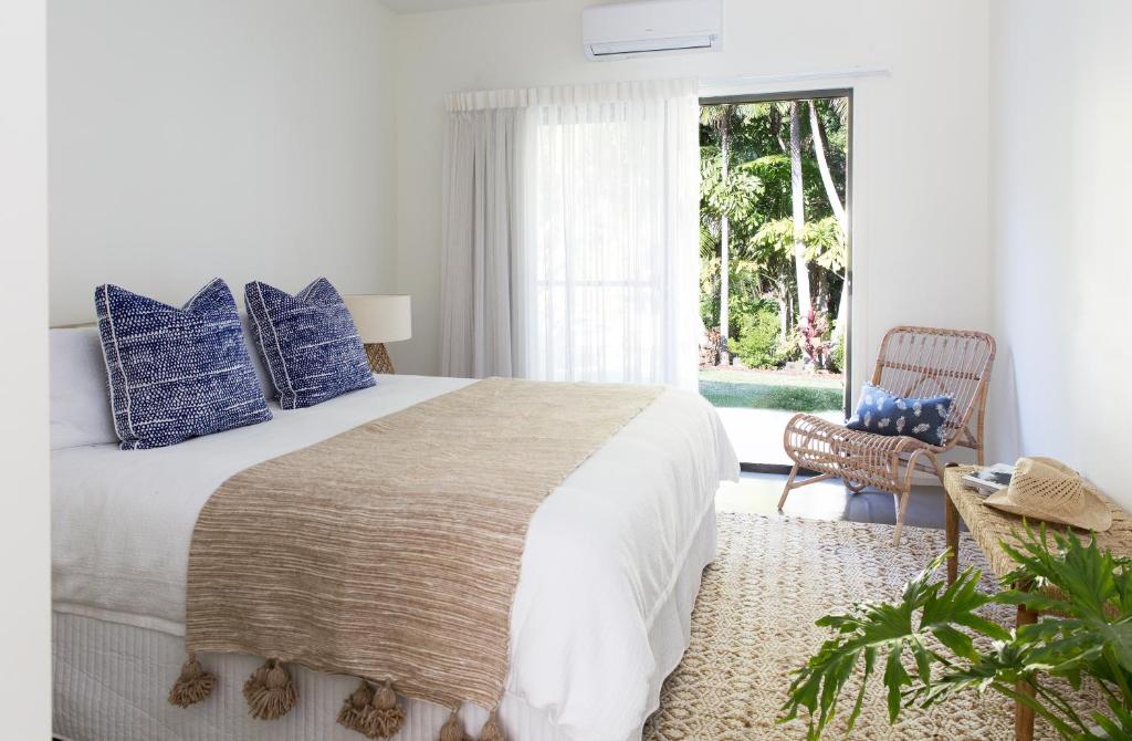 a bedroom with a bed with blue pillows and a window at Satara Byron Bay - Adults Only in Byron Bay