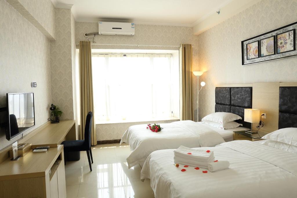 una camera d'albergo con due letti e una televisione di Guangzhou Convention Center Apartment a Canton