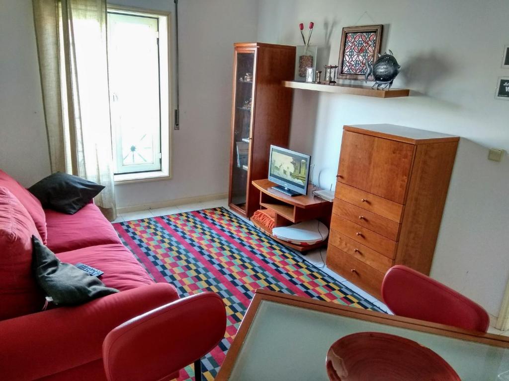Walk Aveiro في أفيرو: غرفة معيشة مع أريكة حمراء ومكتب