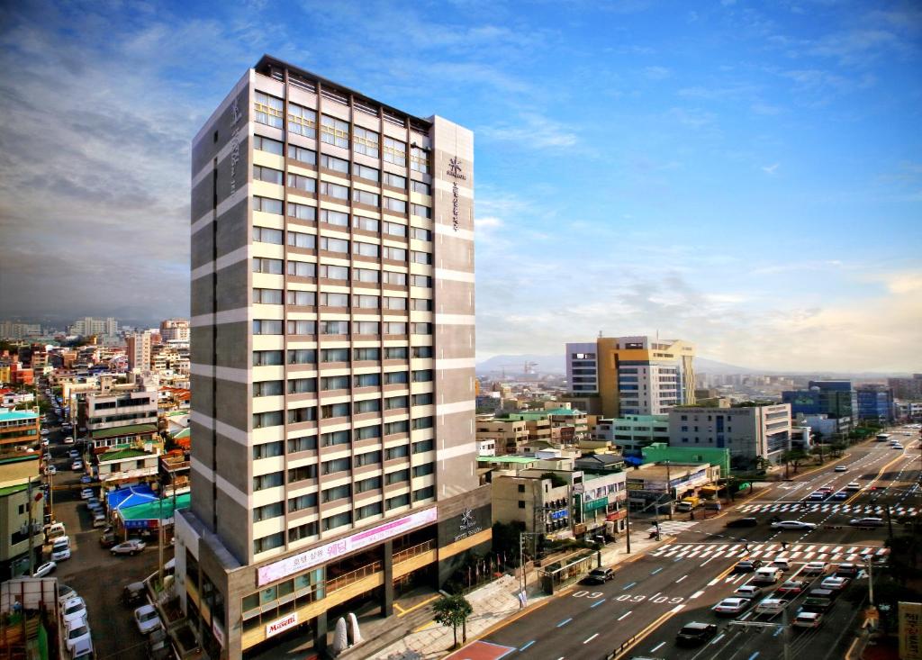 a tall white building in the middle of a city at Hotel Shalom Jeju in Jeju