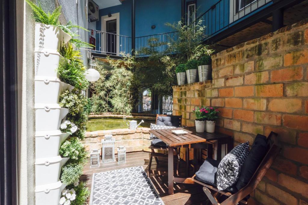 eine Terrasse mit einem Tisch, Stühlen und einer Ziegelwand in der Unterkunft Casinha Azul in Lissabon