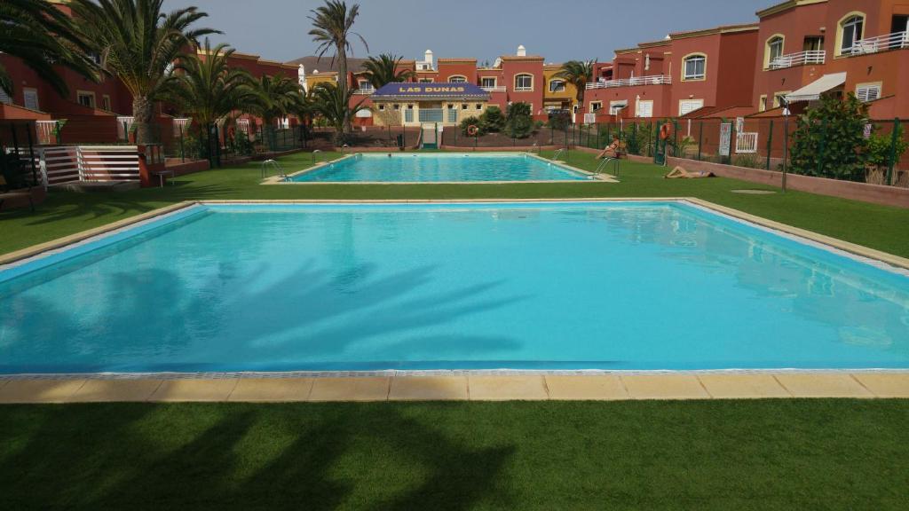 una gran piscina azul junto a algunos apartamentos en Romantic Sunny Apartment, en Corralejo