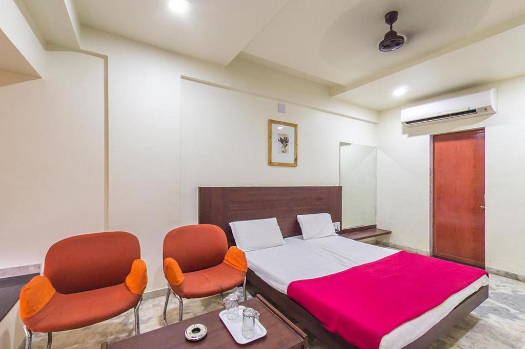 a bedroom with a bed with two chairs and a table at Hotel Rahi Inn in Vadodara