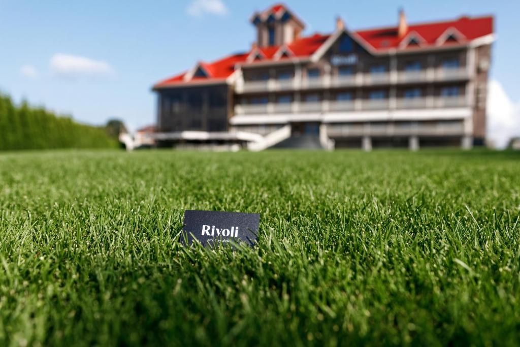 een huis in het midden van een veld van groen gras bij Rivoli Hotel in Tsjernivsi