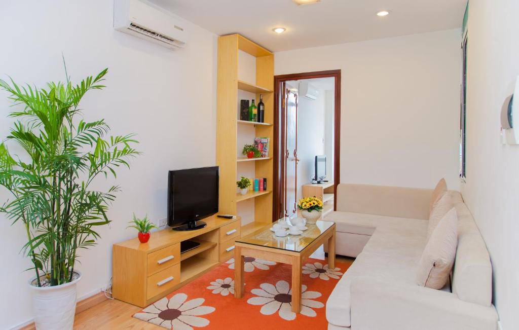 uma sala de estar com um sofá branco e uma televisão em Tài Tâm - Spring Suites em Hanói