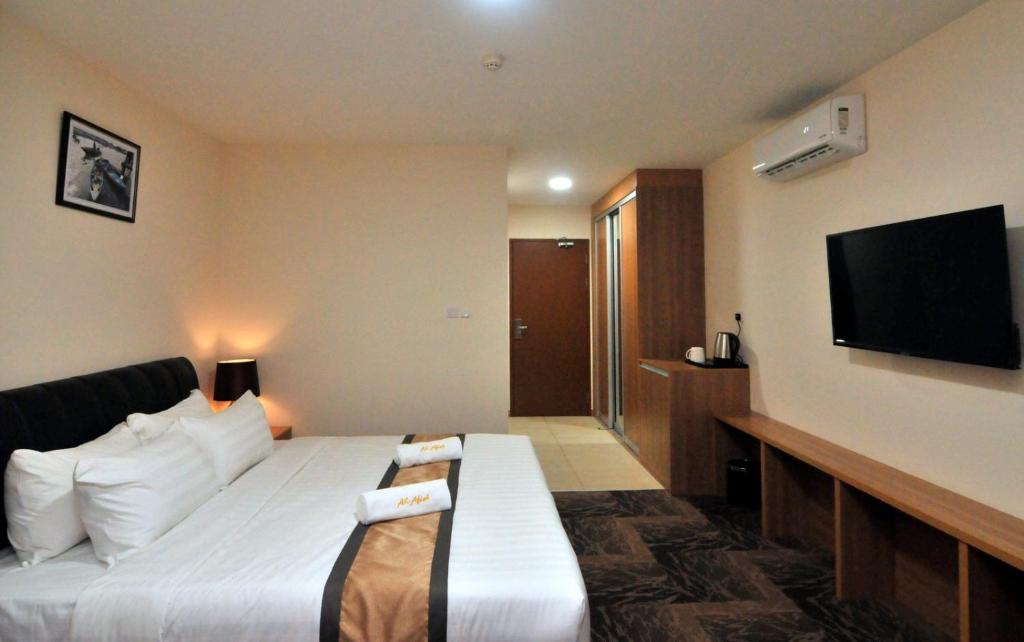 a hotel room with a bed and a flat screen tv at Al Afiah Hotel in Bandar Seri Begawan