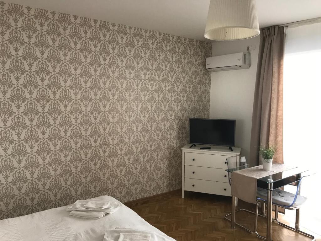 Zimmer mit einem Tisch, einem TV und einem Schreibtisch in der Unterkunft Budapest Downtown Apartments with Balcony & optional Garage & Restaurant in the building in Budapest