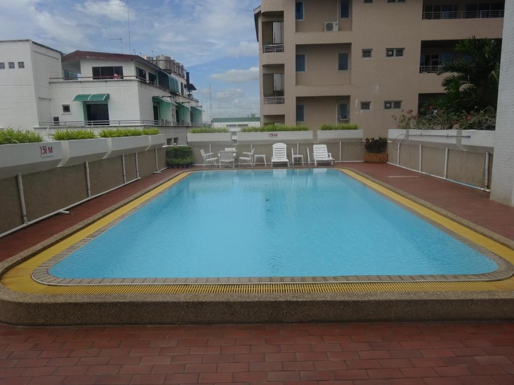 A rooftop swimming pool surrounded by tiled decking and neighboring buildings.