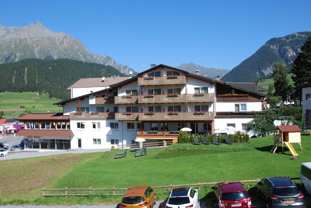 ein großes Gebäude mit davor geparkt in der Unterkunft Alpenhotel Regina in Nauders