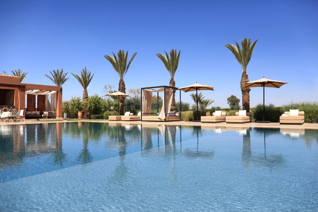 a large swimming pool with umbrellas and palm trees at Dar Sofil - Adults Only in Marrakesh