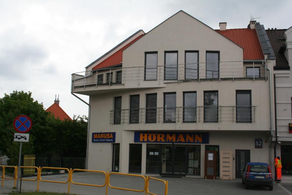 a white building with a balcony on top of it at Pokoje Gościnne Marusa in Szczytno