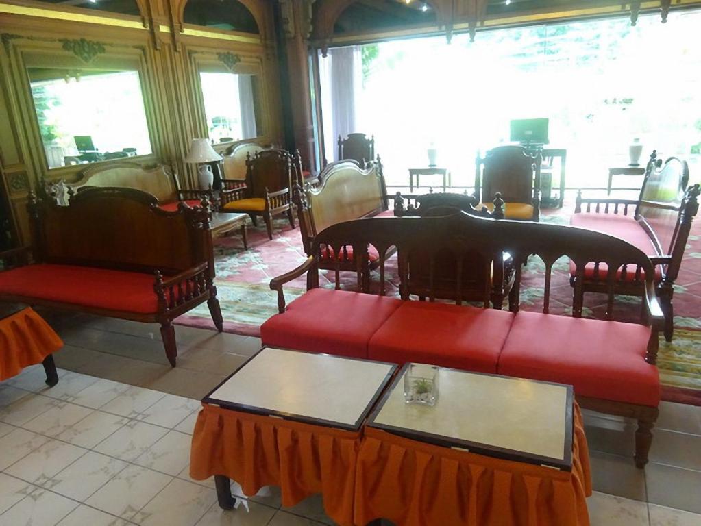 A bright lounge with red-upholstered seating, small tables and large windows.