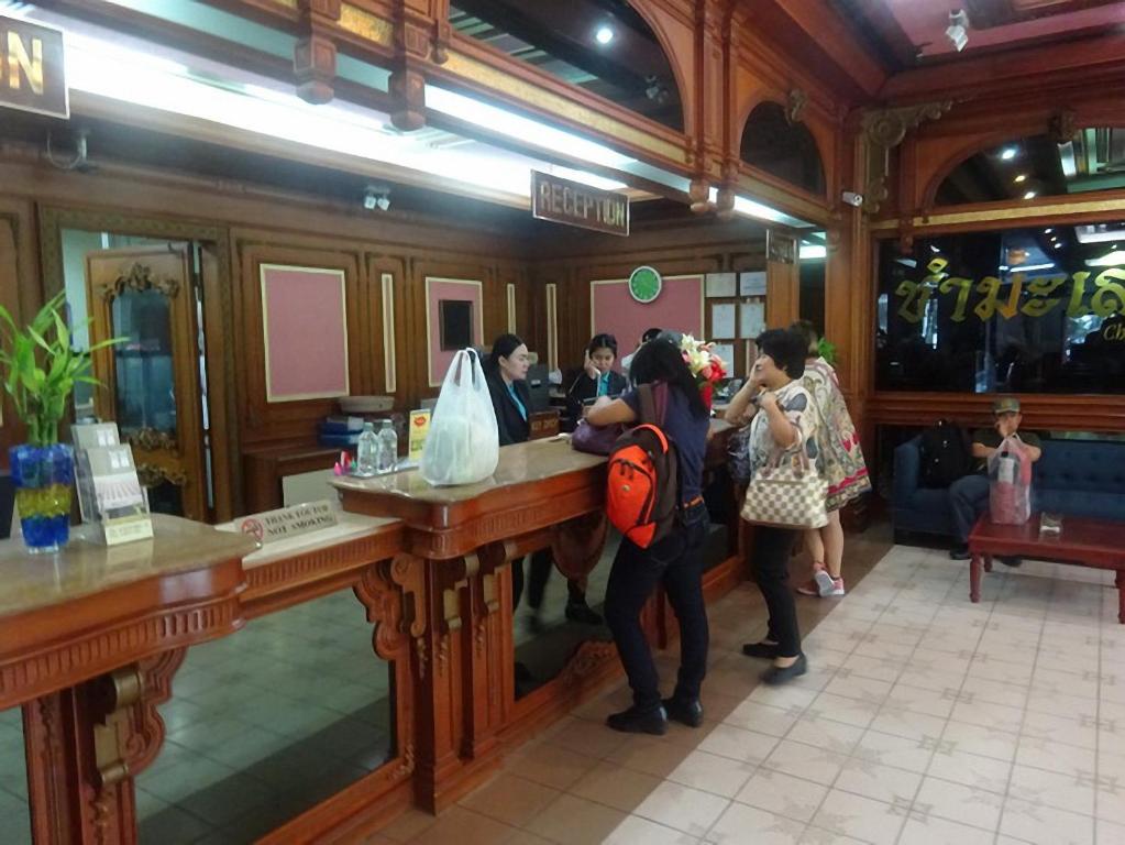 A busy reception counter with staff assisting several guests in a wood-paneled lobby.