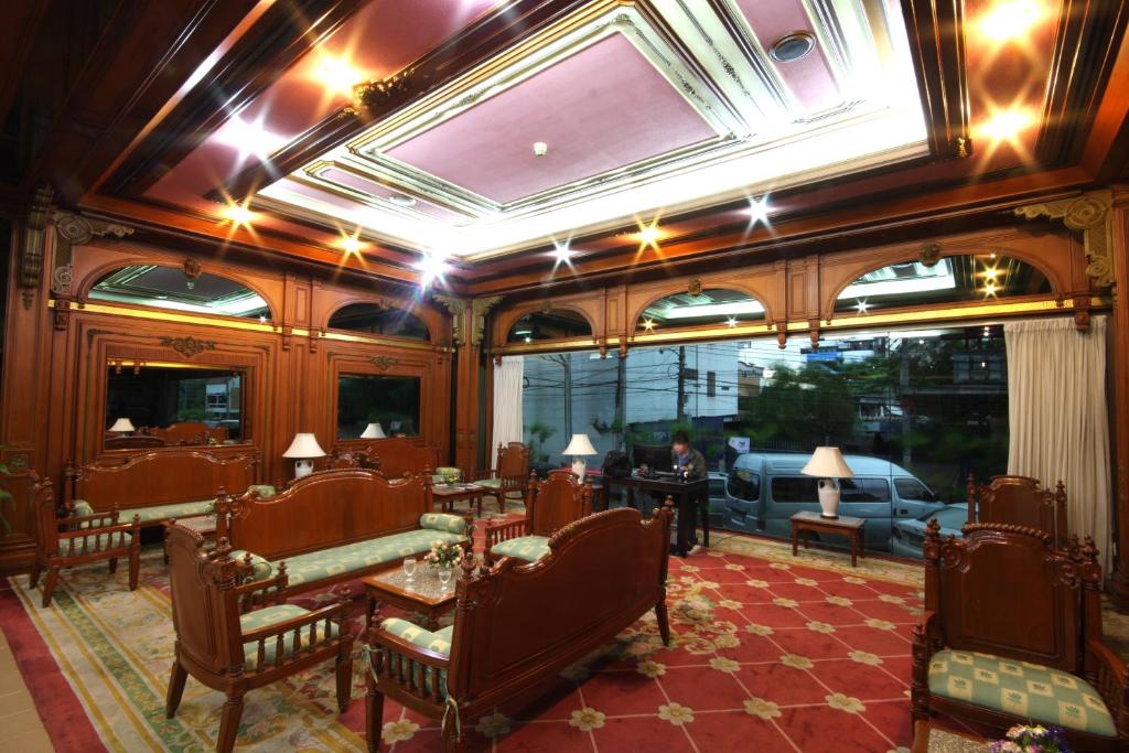A richly furnished lounge with carved wood seating, small tables and large street-facing windows.