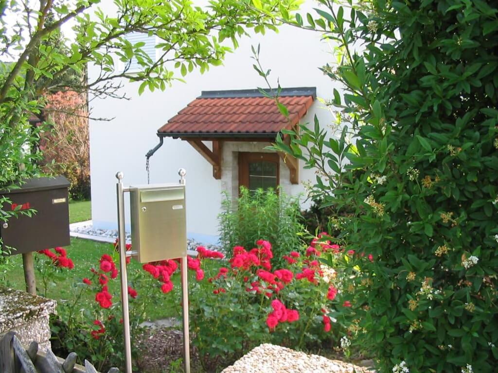 a small house with red flowers in a garden at Ferienwohnung Im Grünen in Illschwang