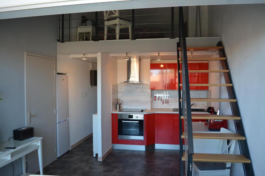 un lit en mezzanine dans une cuisine avec des armoires rouges dans l'établissement Appartement Antinea, au Cap d'Agde