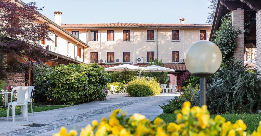 um pátio com cadeiras e guarda-sóis e um edifício em Hotel Al Posta em Casarsa della Delizia