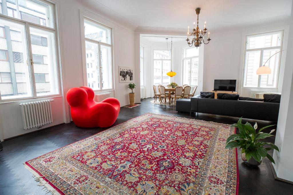 salon z czerwonym krzesłem i dywanem w obiekcie Grand Soho Apartment w Wiedniu