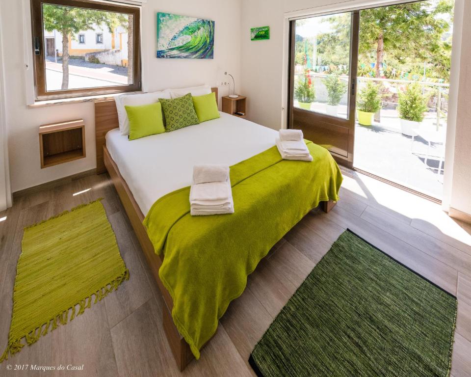 a bedroom with a large bed with a green blanket at Infusion in Óbidos