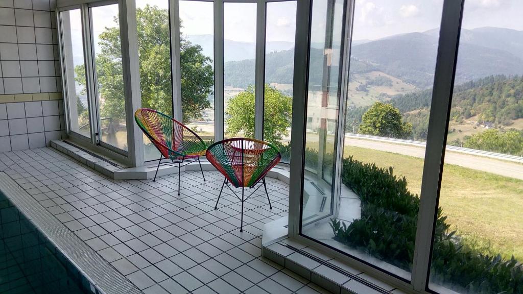 two chairs on a balcony with a view of mountains at Hôtel Panorama in Munster