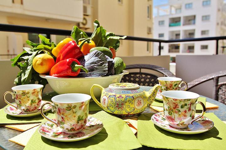 a table with three tea cups and a bowl of fruit at Makenzy Apartment in Larnaka