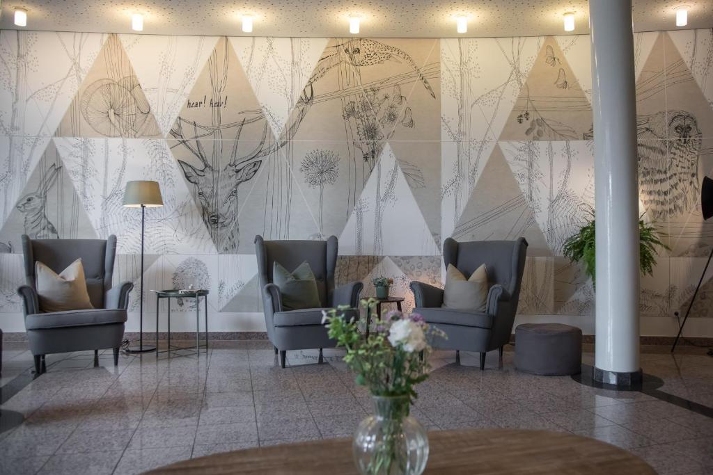 a lobby with chairs and a wall with a mural at Hotel Nickisch in Schüttorf