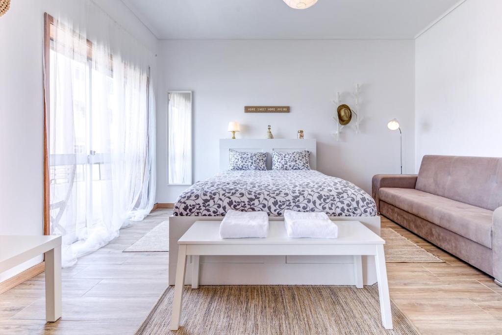 a white bedroom with a bed and a couch at Avenida & Mercado by Home Sweet Home Aveiro in Aveiro