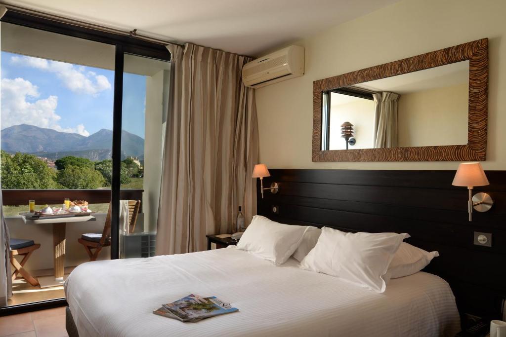 a hotel room with a bed and a large mirror at Hôtel La Roya in Saint-Florent