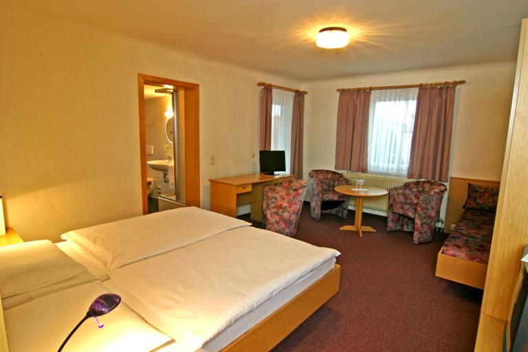 ein Hotelzimmer mit einem Bett, einem Tisch und Stühlen in der Unterkunft Gästehaus Galant in Esslingen