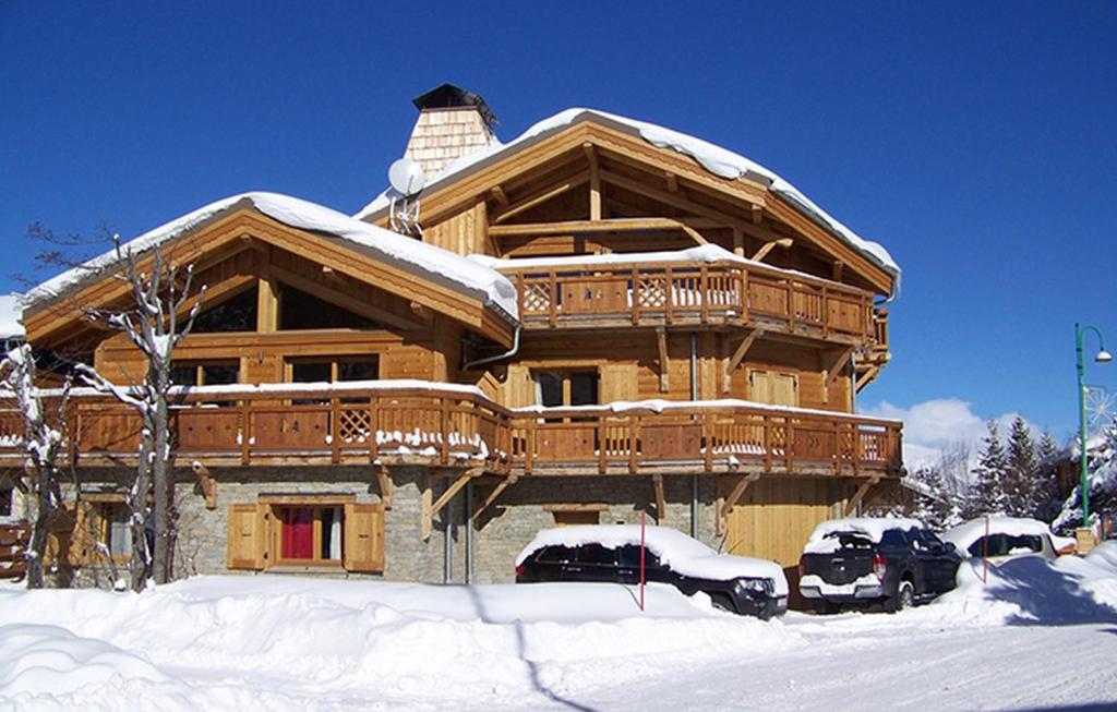 a large wooden house with cars parked in the snow at Odalys Chalet Levanna Occidentale in Les Deux Alpes