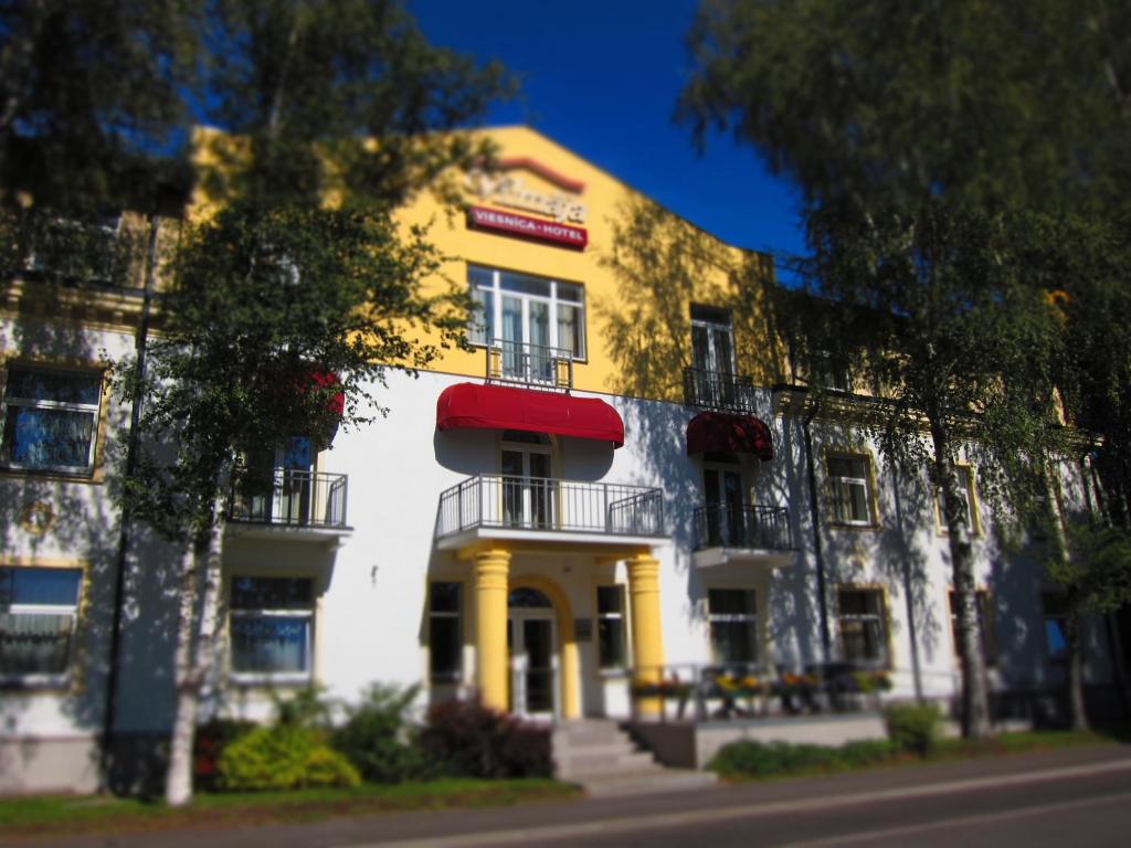 un edificio blanco y amarillo con toldo rojo en Hotel Vilmaja, en Riga
