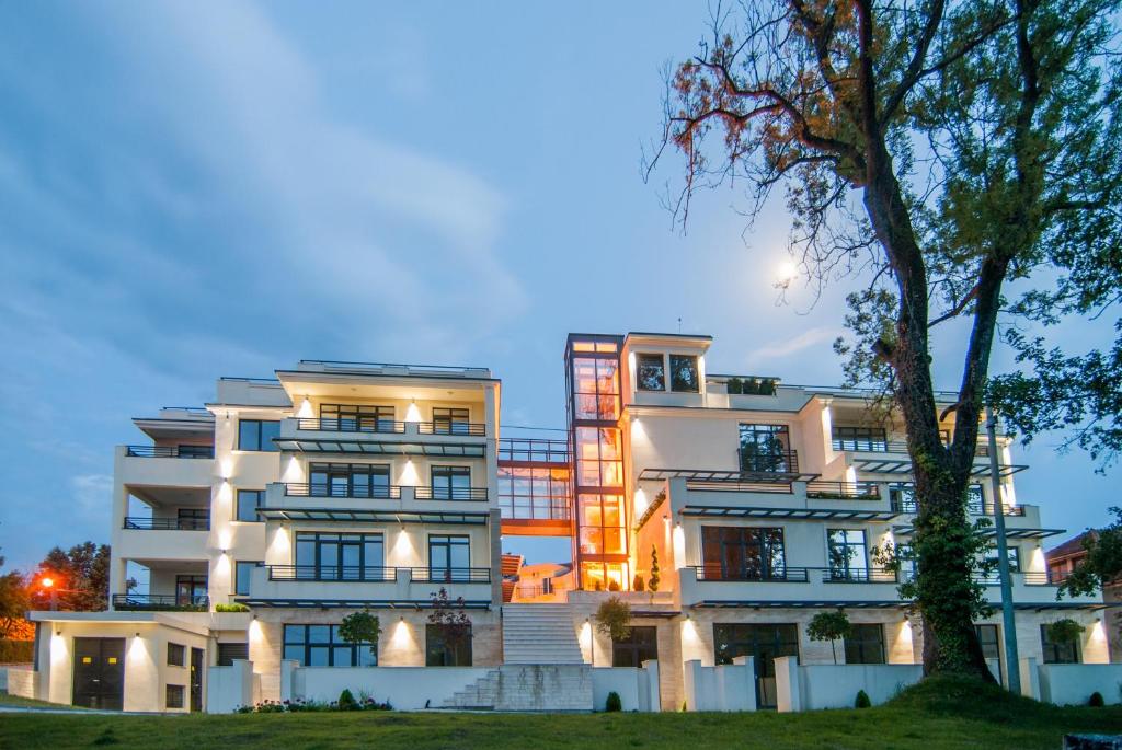 un bâtiment blanc avec un arbre devant lui dans l'établissement Vila Opera, à Vrnjačka Banja