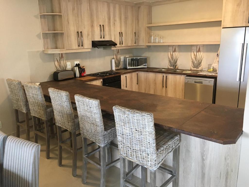 a kitchen with a wooden counter with chairs and a refrigerator at Sunset Heights in Langebaan