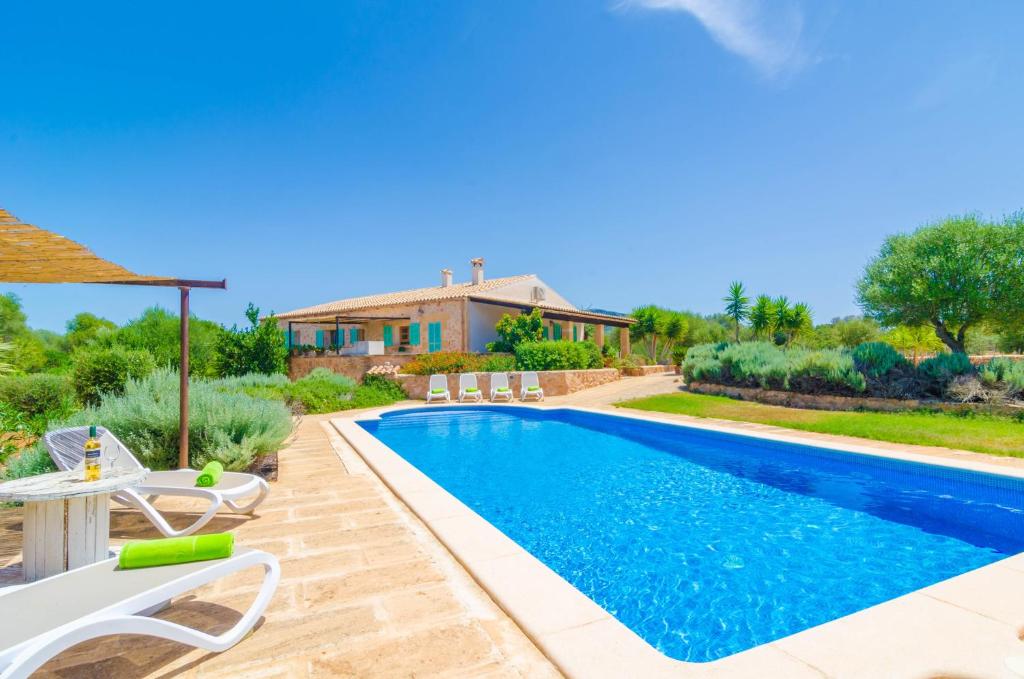 uma piscina com cadeiras e uma casa em Casa Yolanda em Manacor