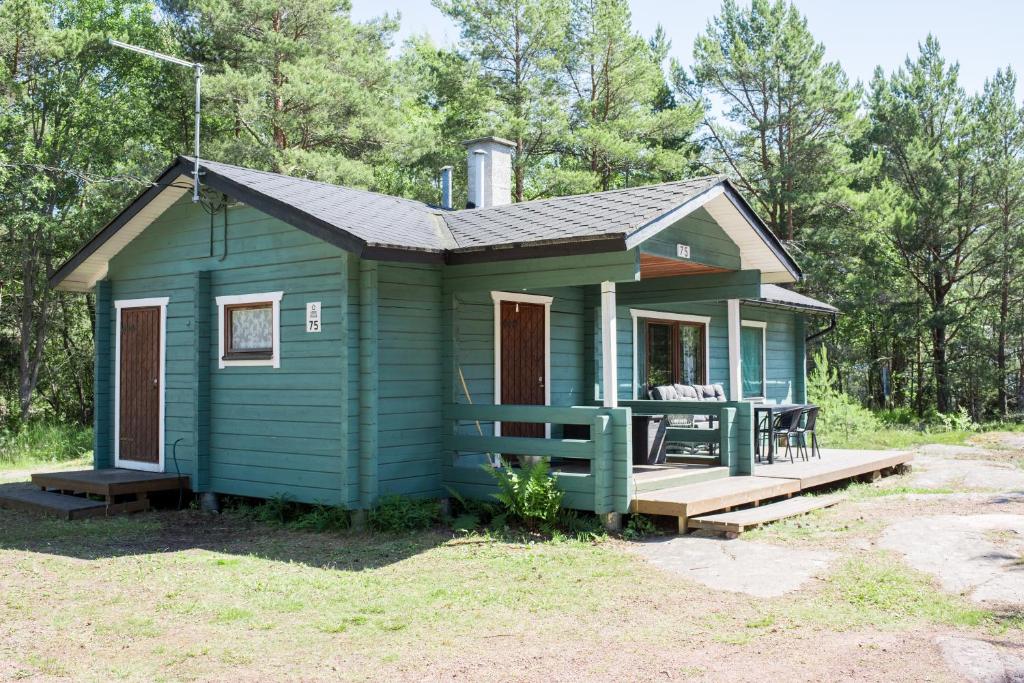 a green tiny house with a porch and a deck at Herrö stugor in Lemland