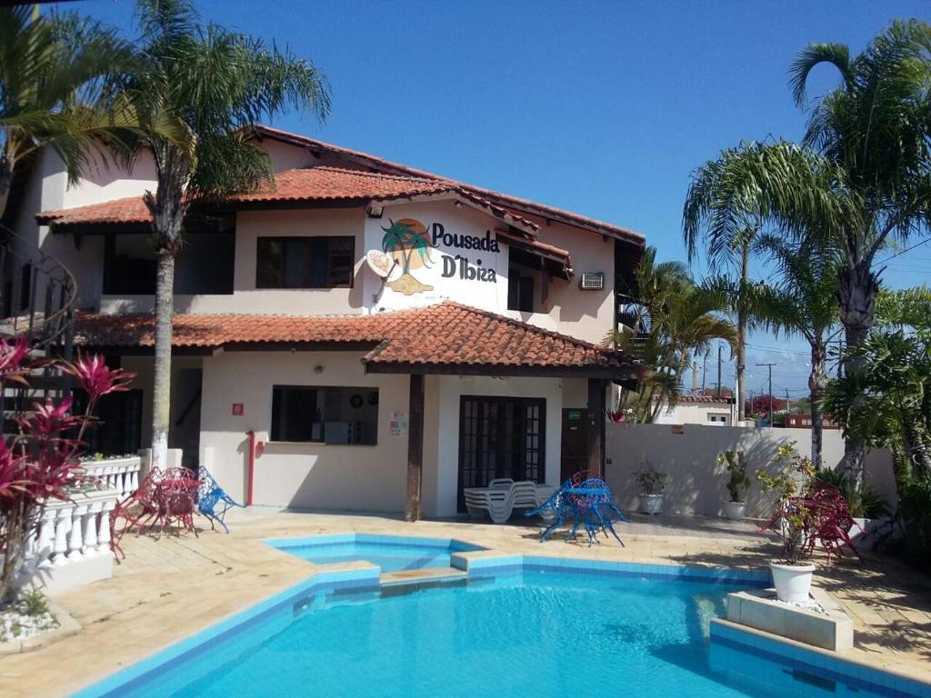 a hotel with a swimming pool in front of a building at Pousada d'Ibiza in Itanhaém