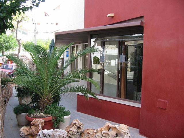un edificio rojo con algunas plantas delante de él en Hostal Residencia Sutimar en Paguera