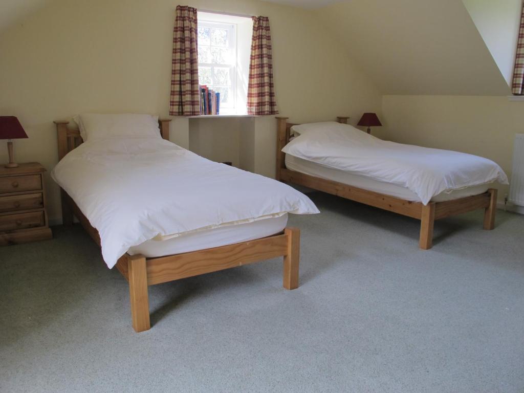 two twin beds in a bedroom with a window at Cumledge Yew Trees Cottage in Duns