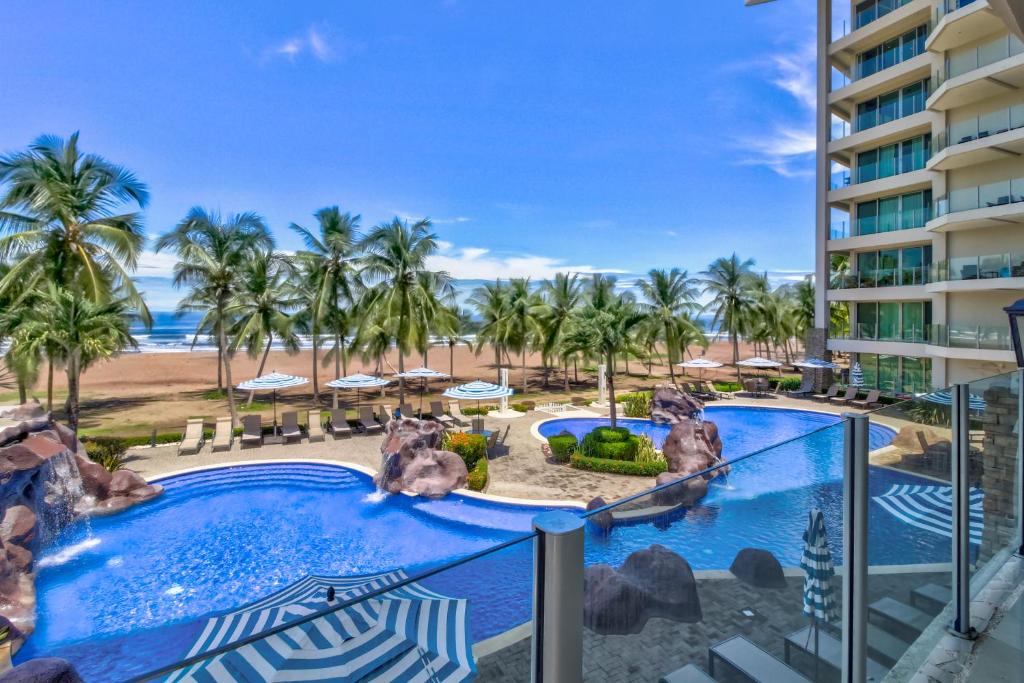 a view of the pool and beach from the balcony of a resort at Diamante del Sol 203S in Jacó