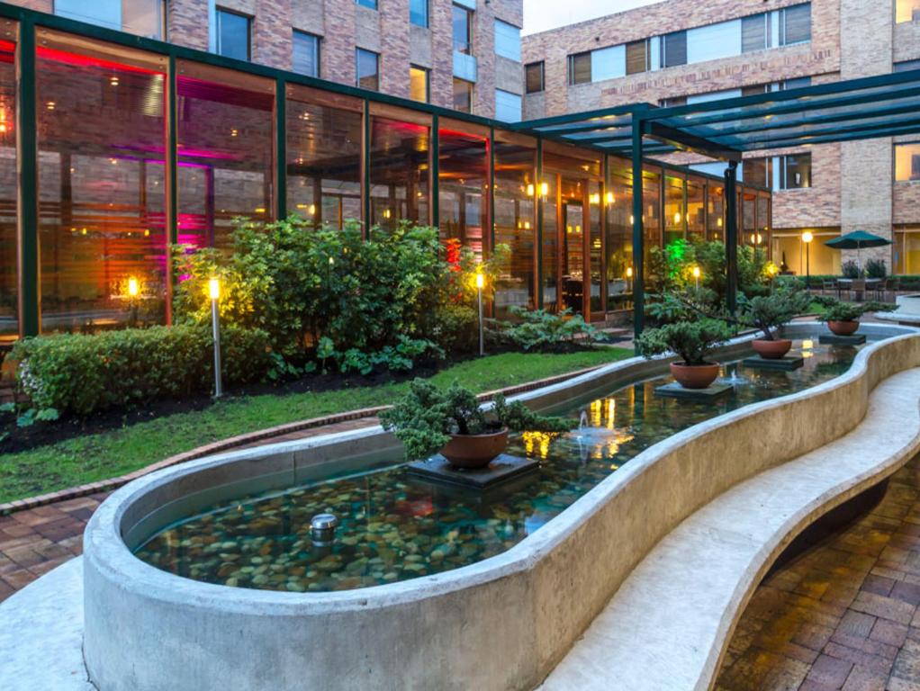 a large building with a pond in front of a building at Hotel Habitel Select in Bogotá
