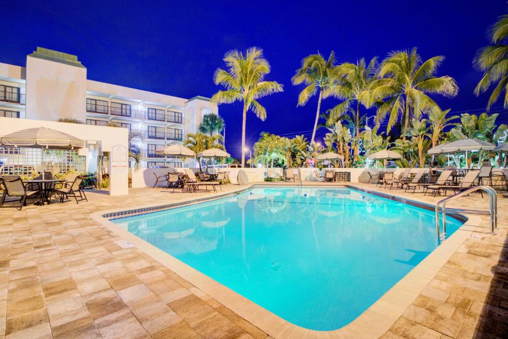 a pool at night with tables and chairs and palm trees at Boca Plaza in Boca Raton
