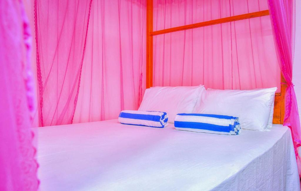 2 almohadas en una cama en una tienda rosa en Bayview Seafood rest, en Weligama