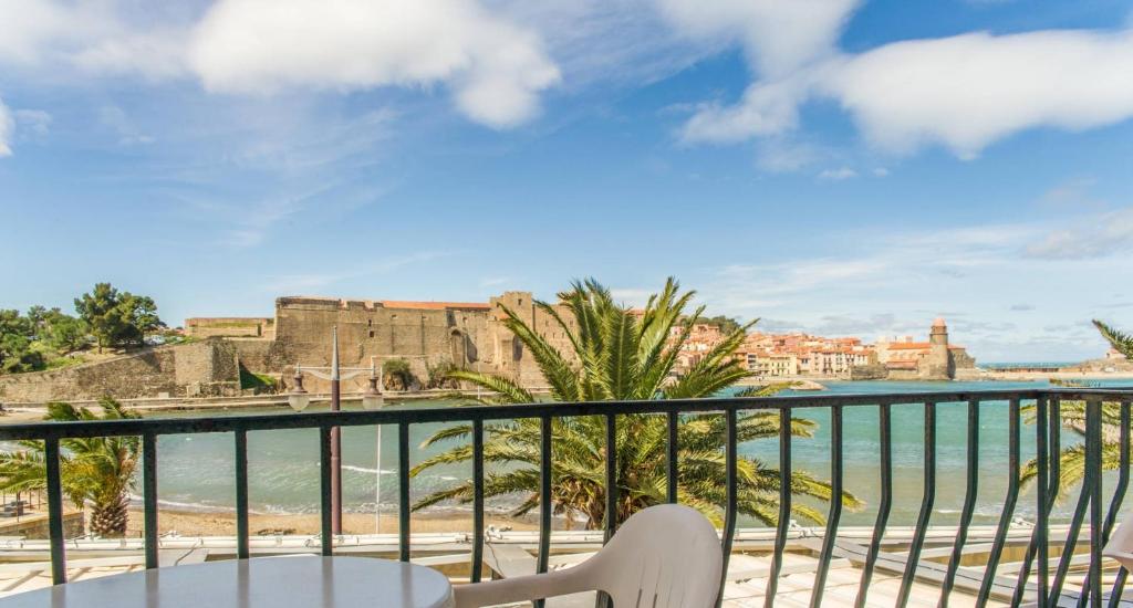a balcony with a table and chairs and a view of the ocean at Hôtel Triton in Collioure