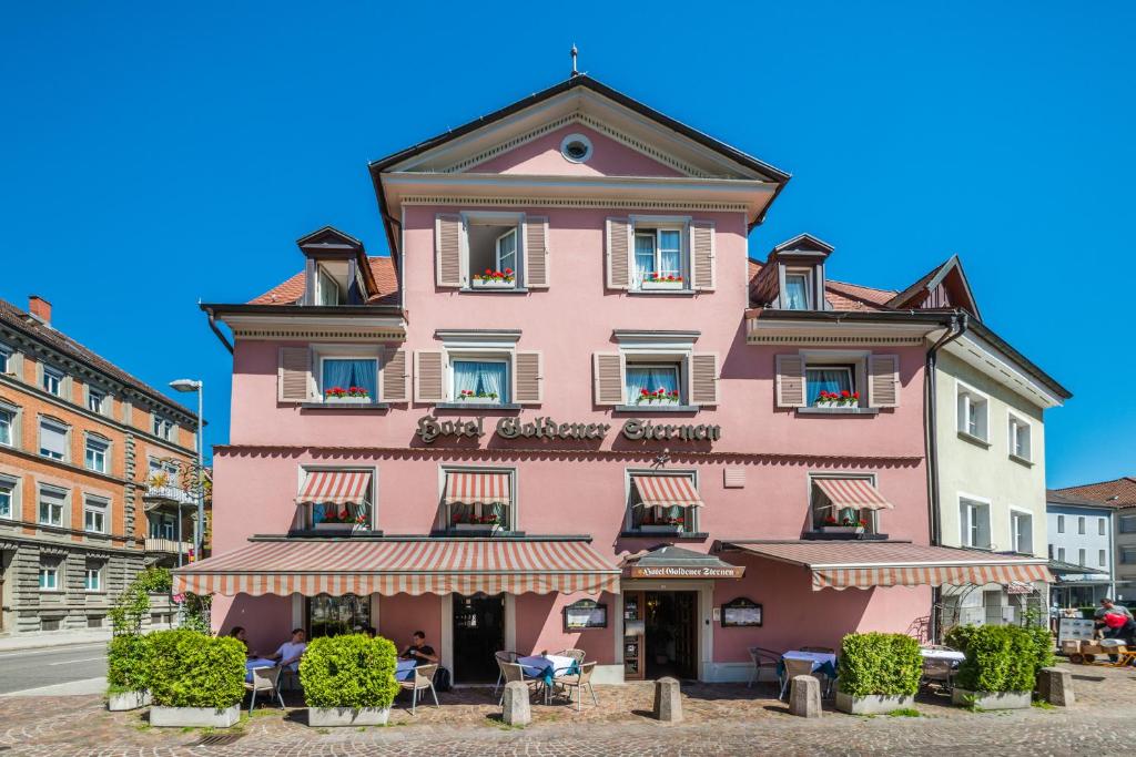 un bâtiment rose au milieu d'une rue dans l'établissement Hotel Goldener Sternen, à Constance