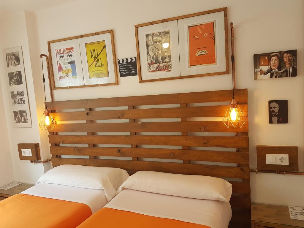 two beds in a bedroom with a wooden headboard at Barri Antic Hostel & Pub in Andorra la Vella