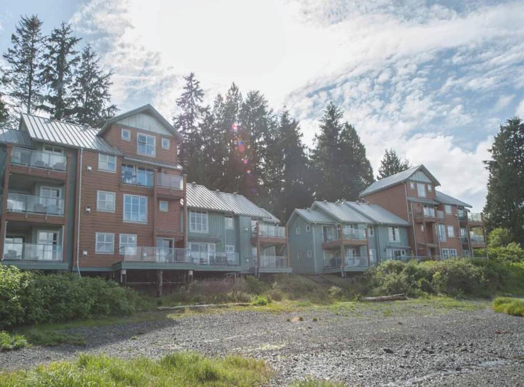 un grupo de casas con una montaña en el fondo en Luxury 2BR Oceanfront Condo by OnlyBC 201, en Tofino