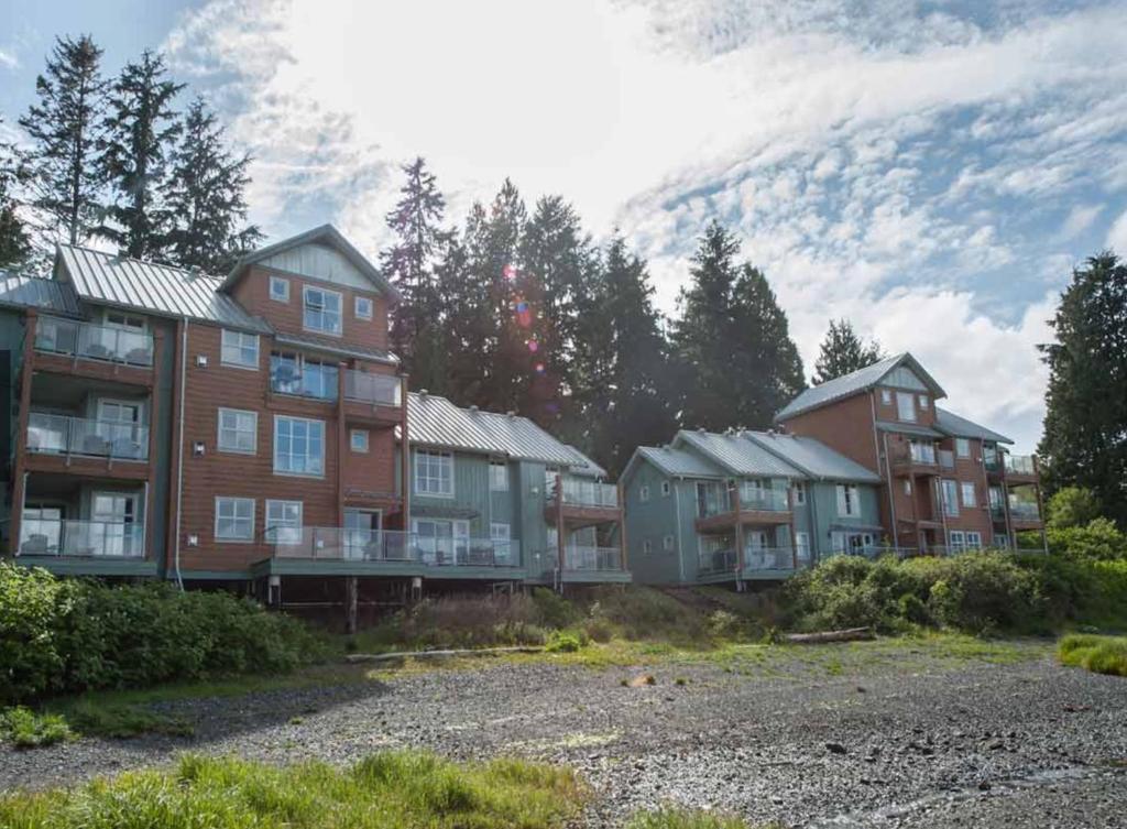 a group of houses with a mountain in the background at Waterfront Condo by OnlyBC 202 in Tofino