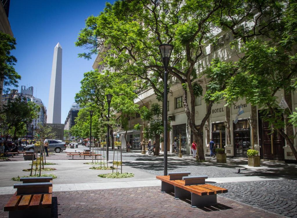 een stadsstraat met banken, bomen en gebouwen bij Unique Executive Central in Buenos Aires